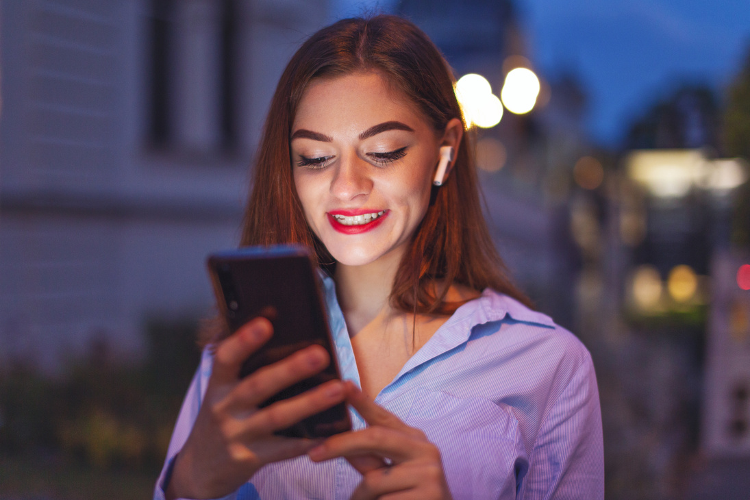 Young celebrity checking social media profile at night in city
